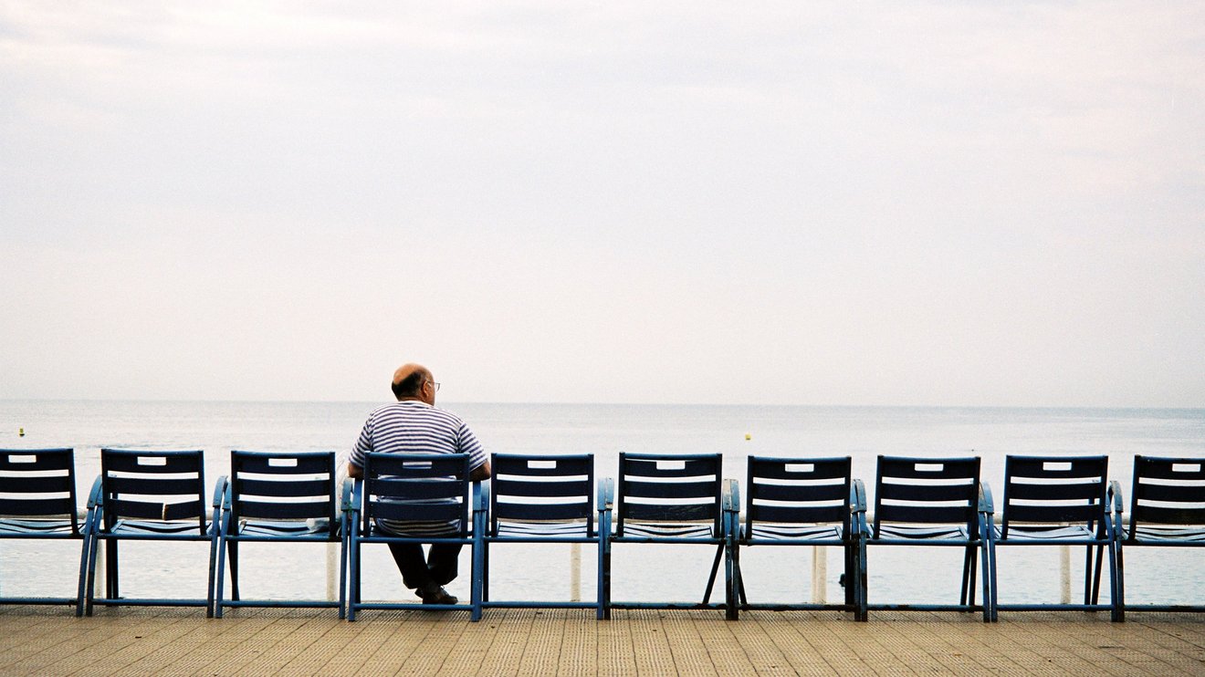 Mann sitzt allein auf einer Bank